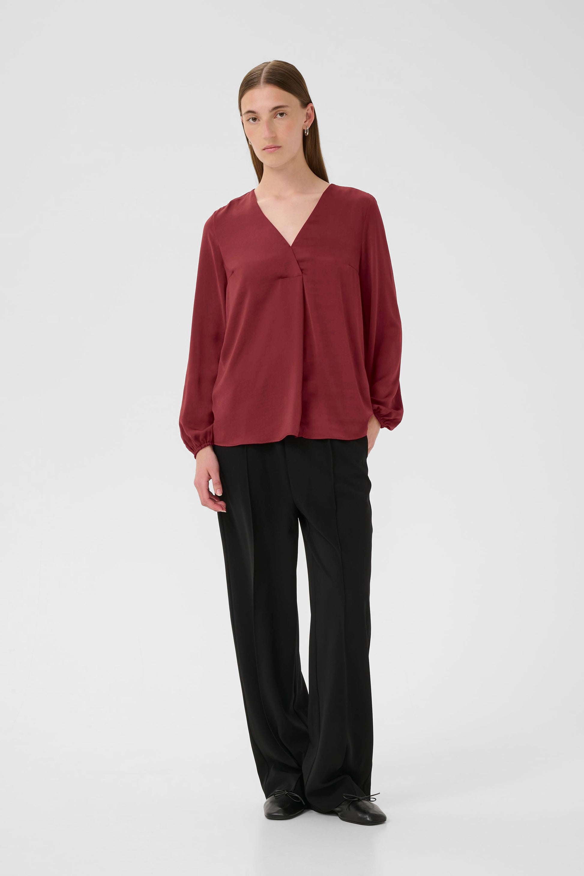 Woman wearing a burgundy Blouse with long sleeves and V Neck on a white background