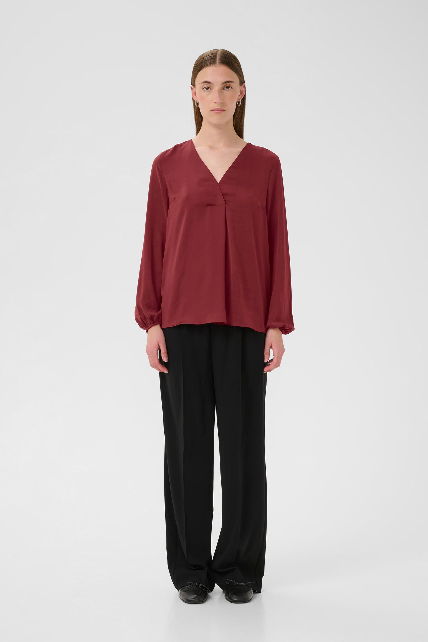 Woman wearing a burgundy Blouse with long sleeves and V Neck on a white background
