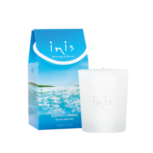 Picture of the Inis candle in a white frosted glass holder and the box which is blue with the picture of the sea on