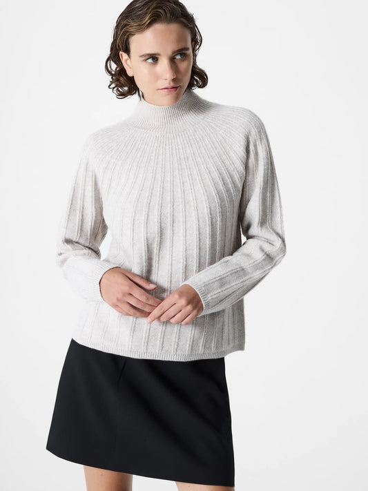 woman wearing a ribbed light colour jumper with a mock neck.  Long sleeves