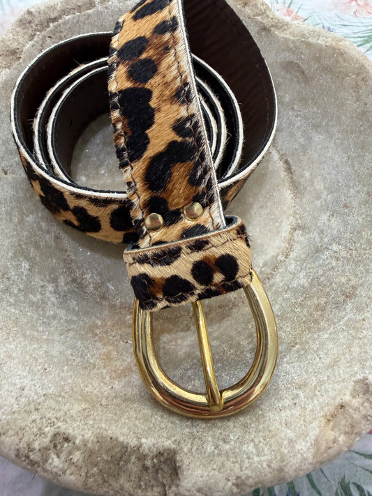 Leopard print belt with a gold buckle on a stone surface