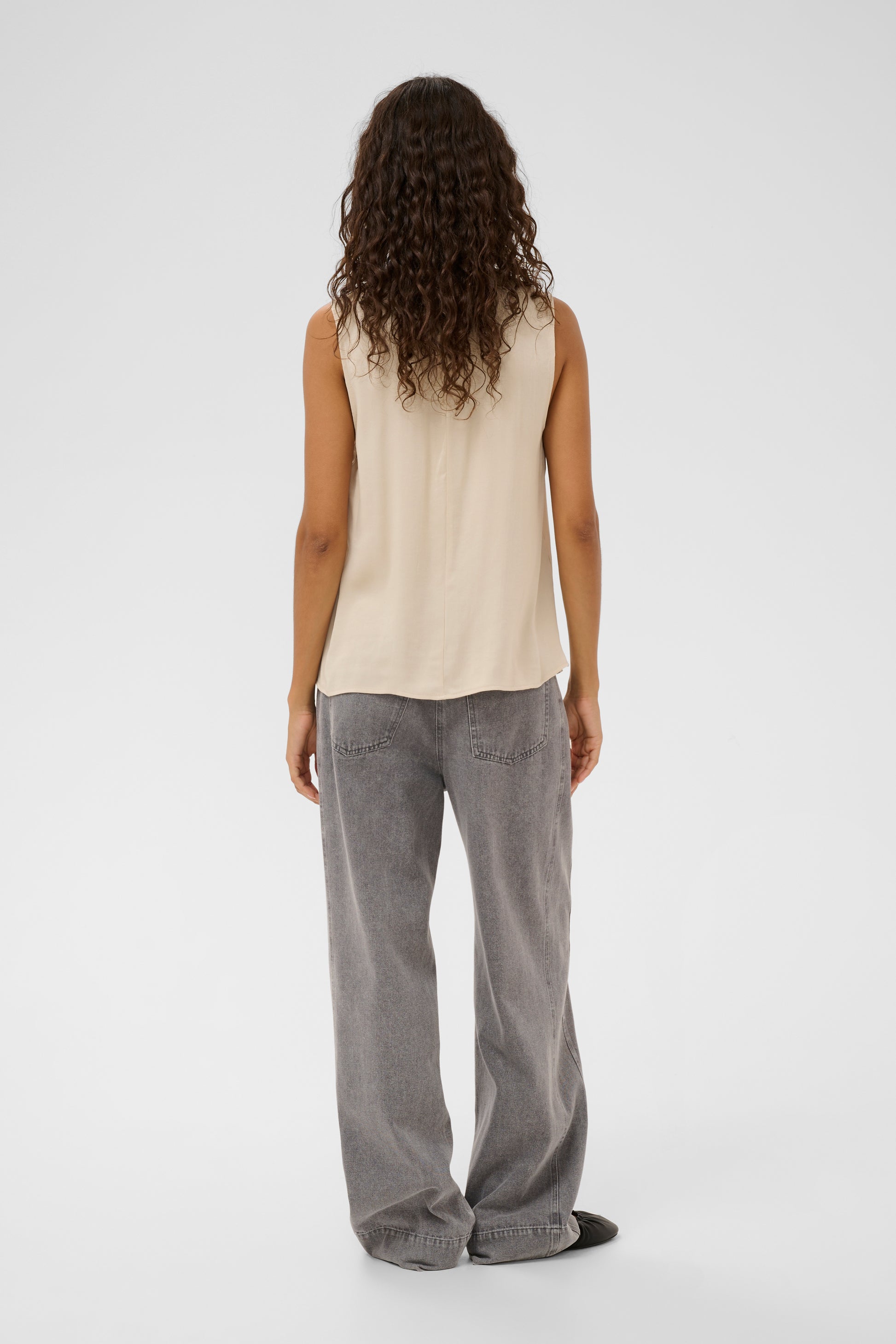 Woman wearing the soaked in luxury nadeya miria  beige sleeveless blouse with a tie neckline.