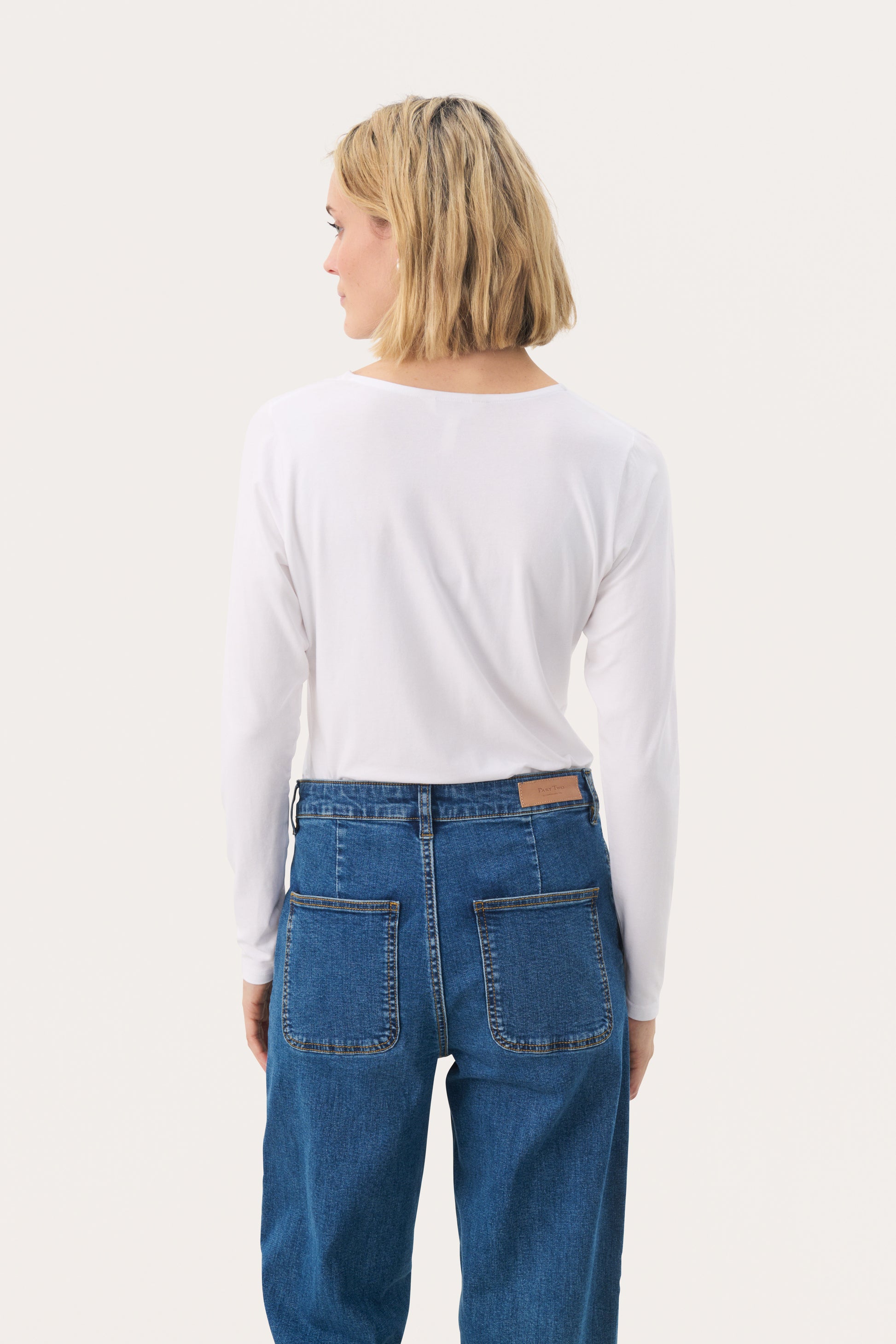 Woman wearing a white long sleeved top and jeans
