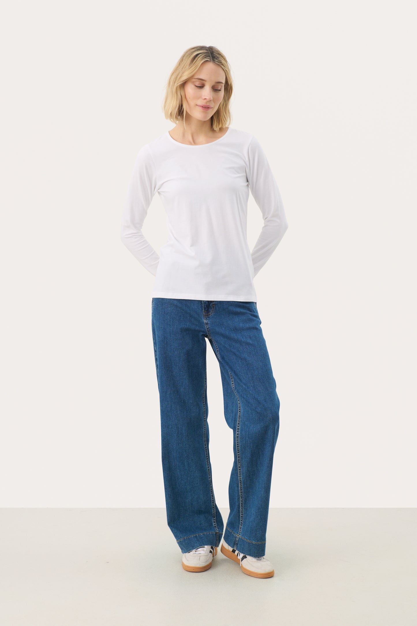 Woman wearing a white long sleeved top and jeans