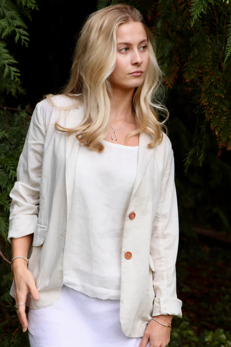 Woman wearing a light-colored cardigan over a white top with a blurred natural background