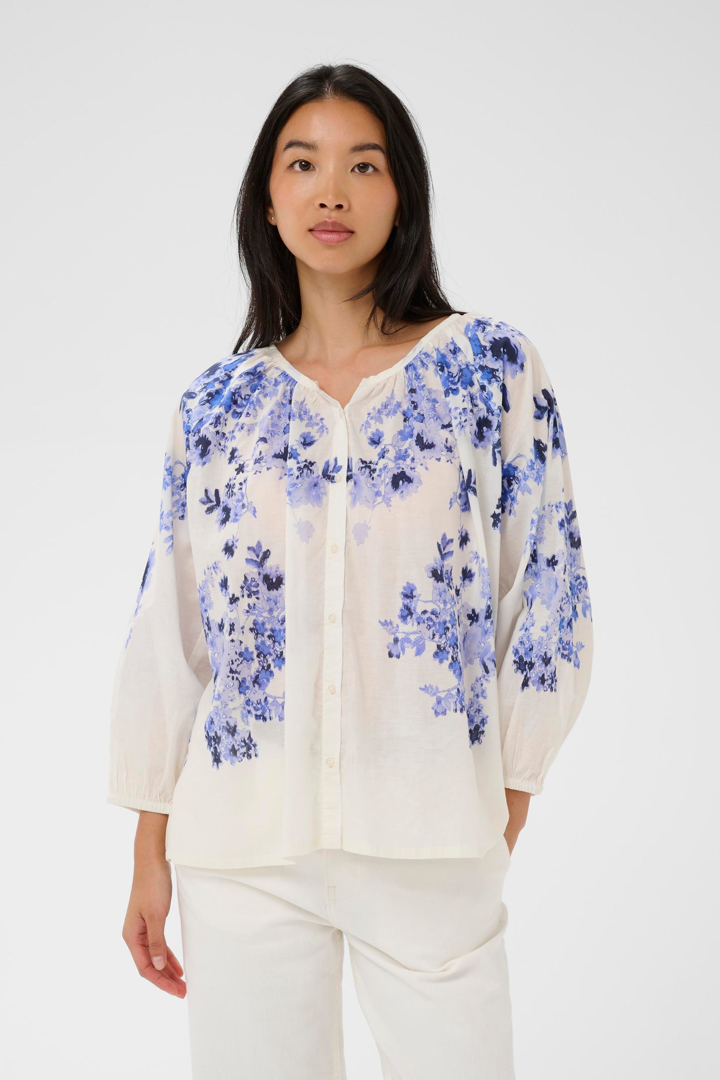 Woman wearing the Part Two Alexi  blue floral blouse and white pants on a white background