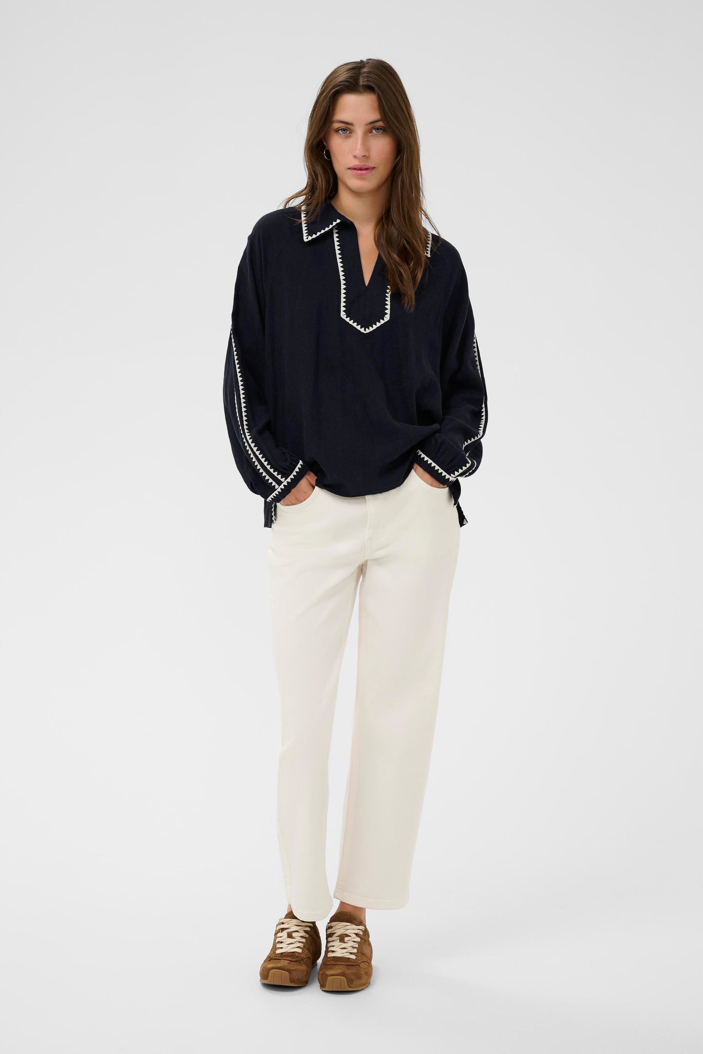 Woman wearing the part two Aimy Linen blend navy  blouse with white trim and white pants on a white background