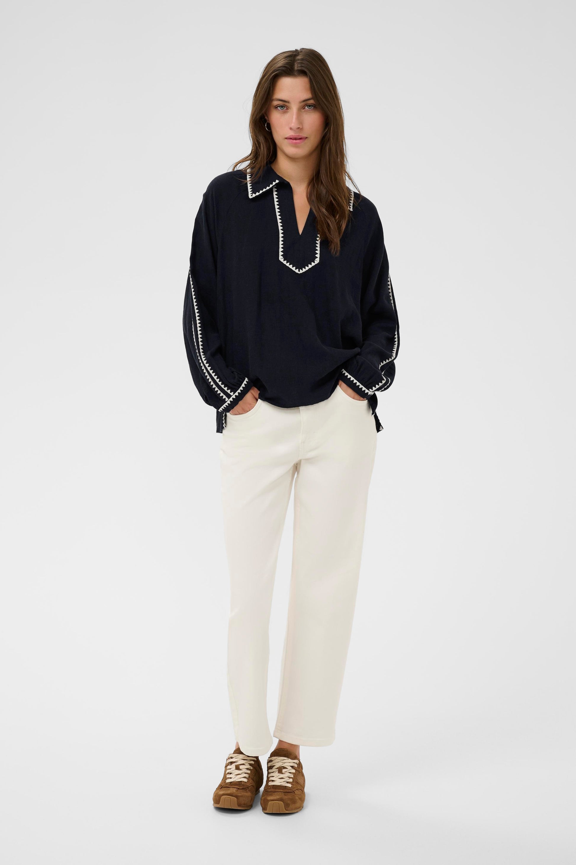 Woman wearing the part two Aimy Linen blend navy  blouse with white trim and white pants on a white background