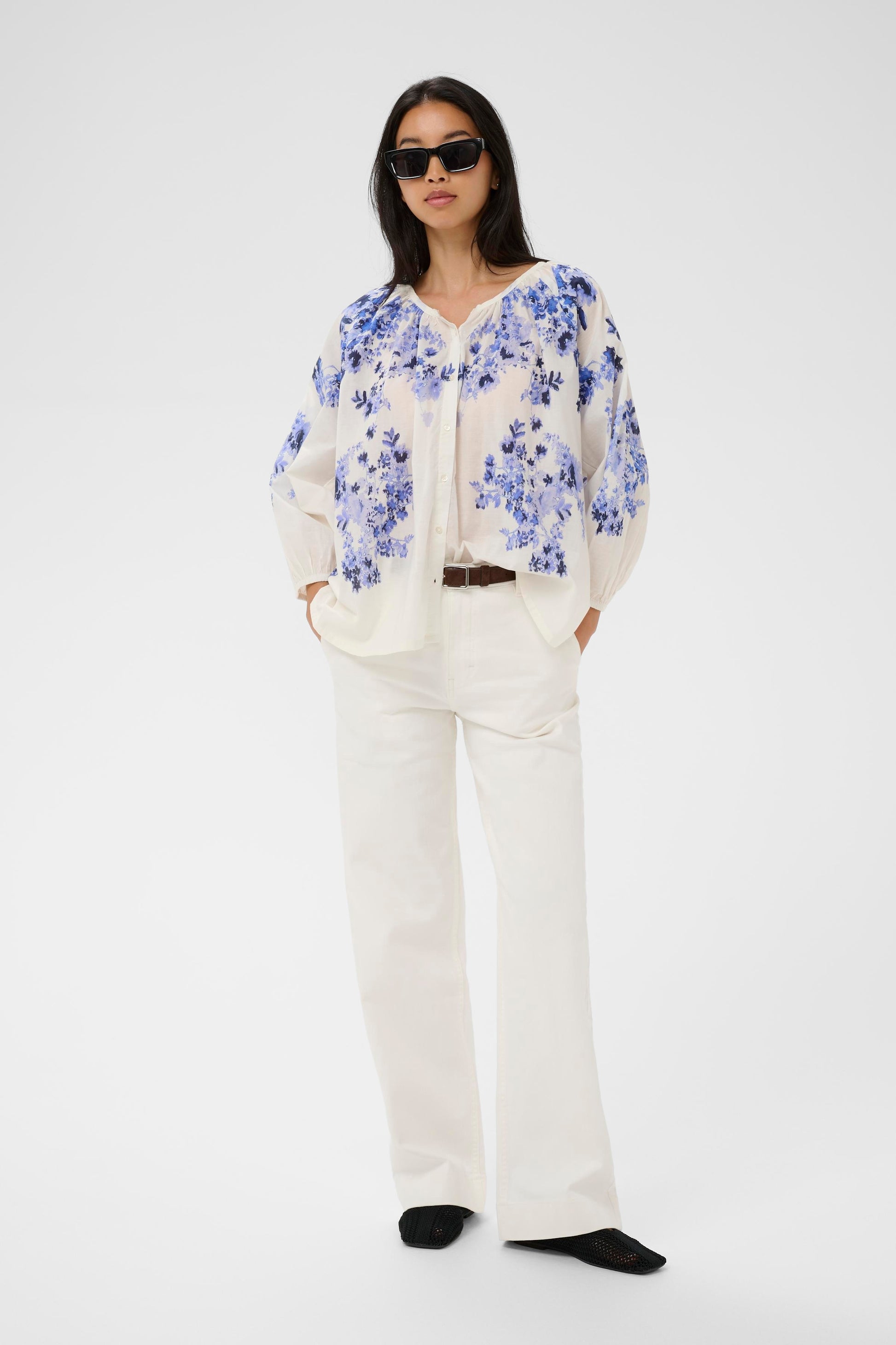 Woman wearing the Part Two Alexi  blue floral blouse and white pants on a white background