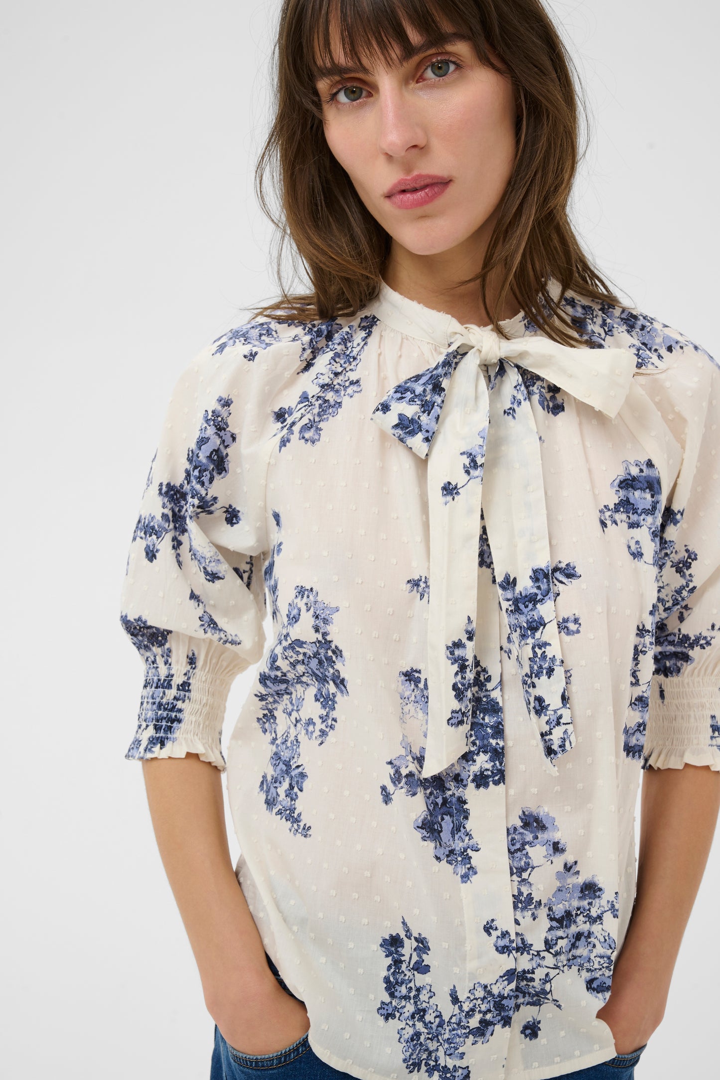 Woman wearing the Part Two Almera blue and white floral blouse and blue jeans on a white background
