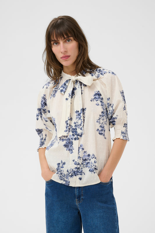 Woman wearing the Part Two Almera blue and white floral blouse and blue jeans on a white background