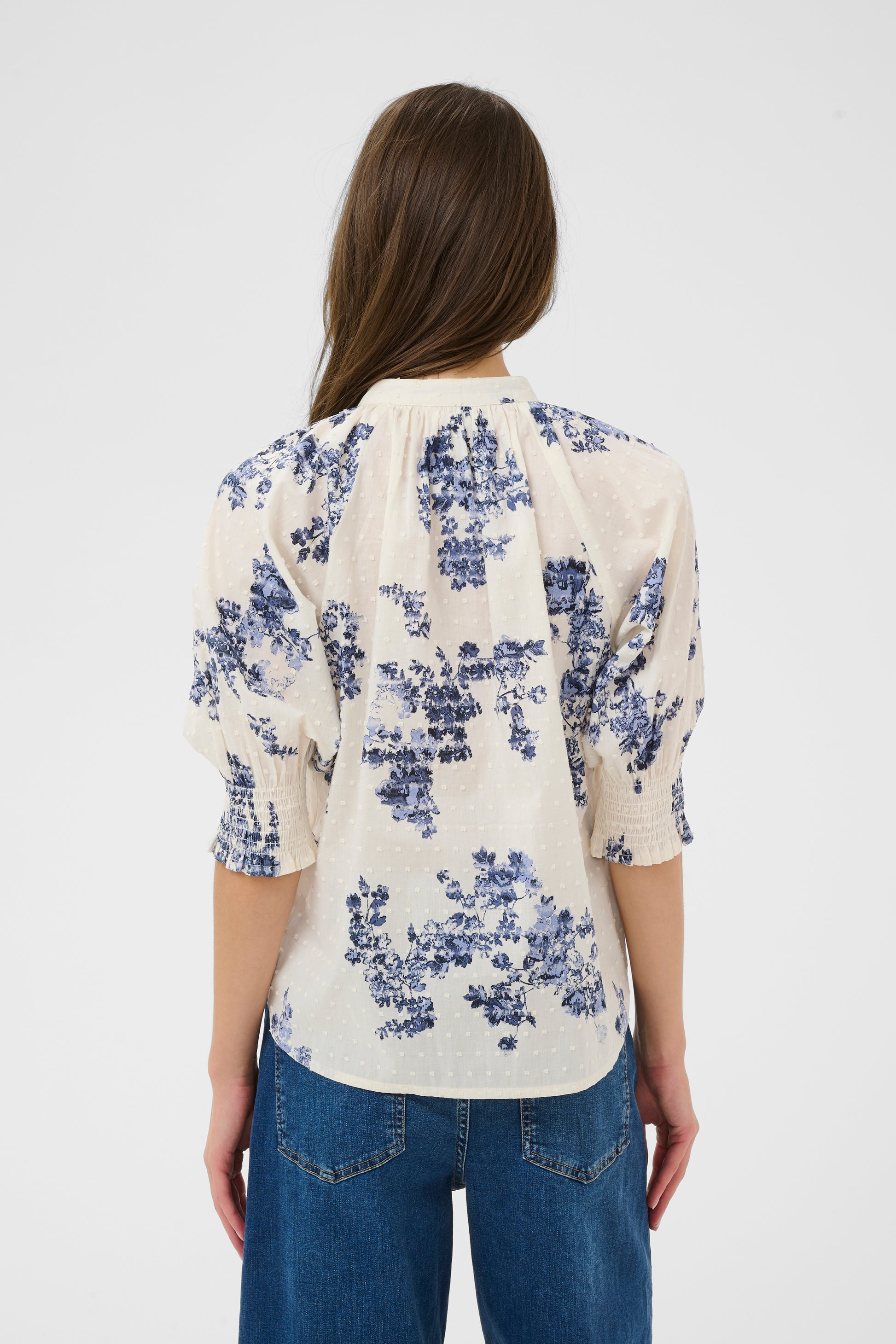 Woman wearing the Part Two Almera blue and white floral blouse and blue jeans on a white background