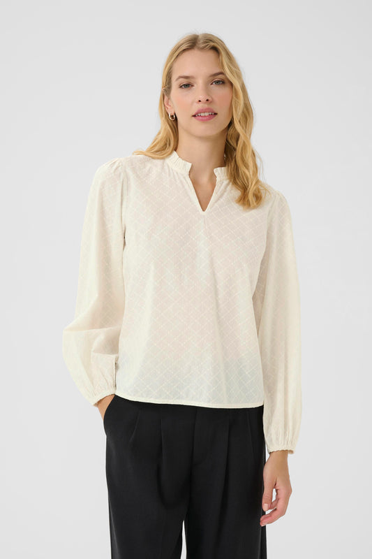 Woman wearing a light-colored blouse and black pants on a white background