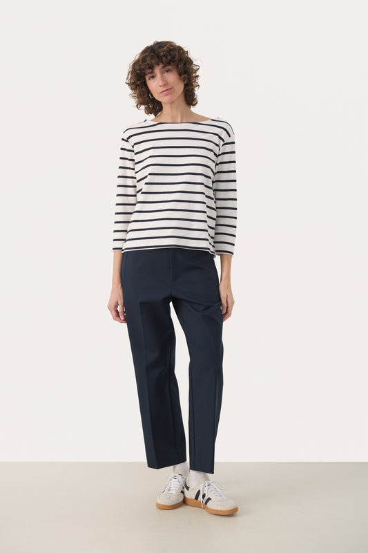 Woman wearing a 3/4 length sleeve white top with dark navy stripes. 