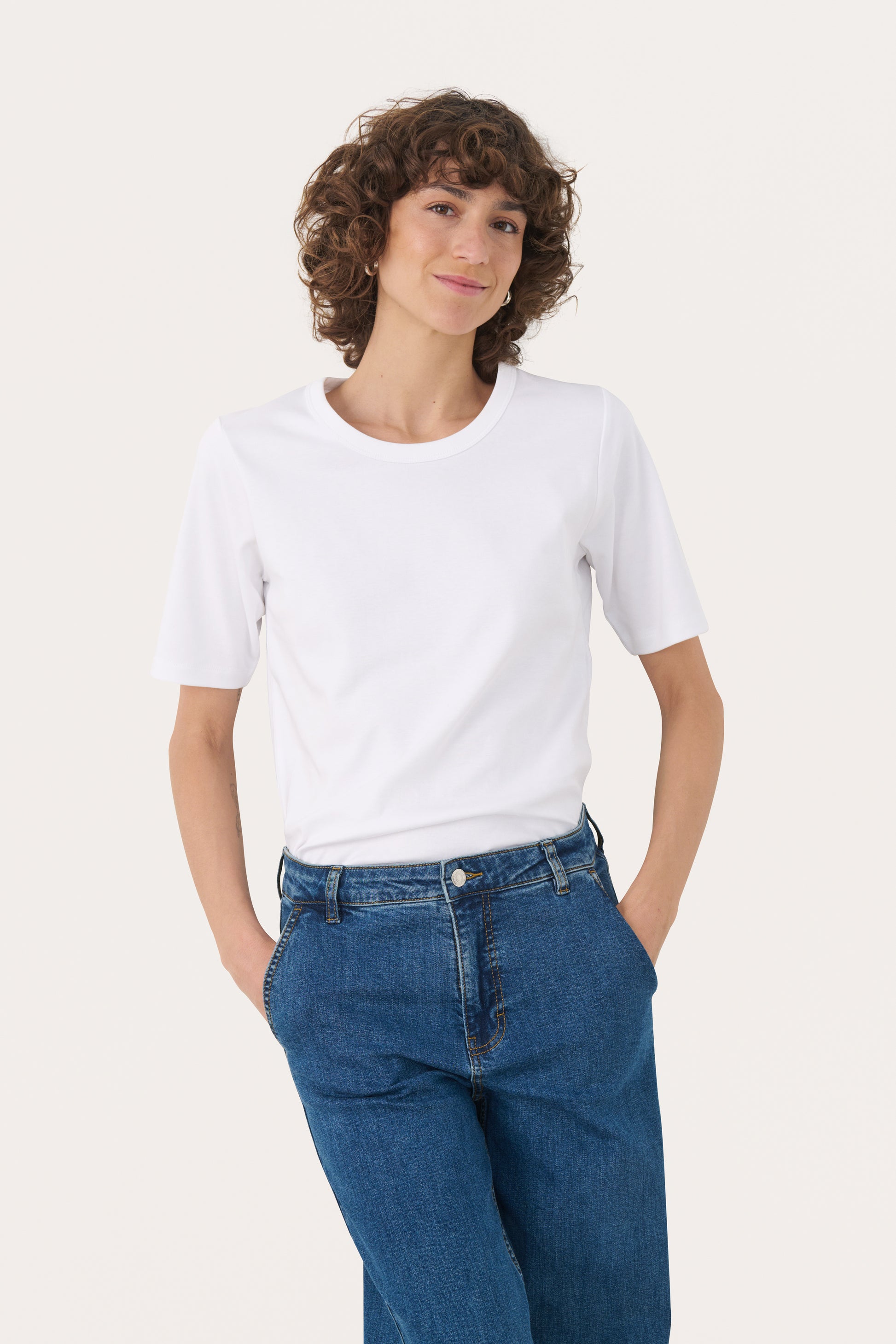 Person wearing the part two ratana white t-shirt and blue jeans on a white background