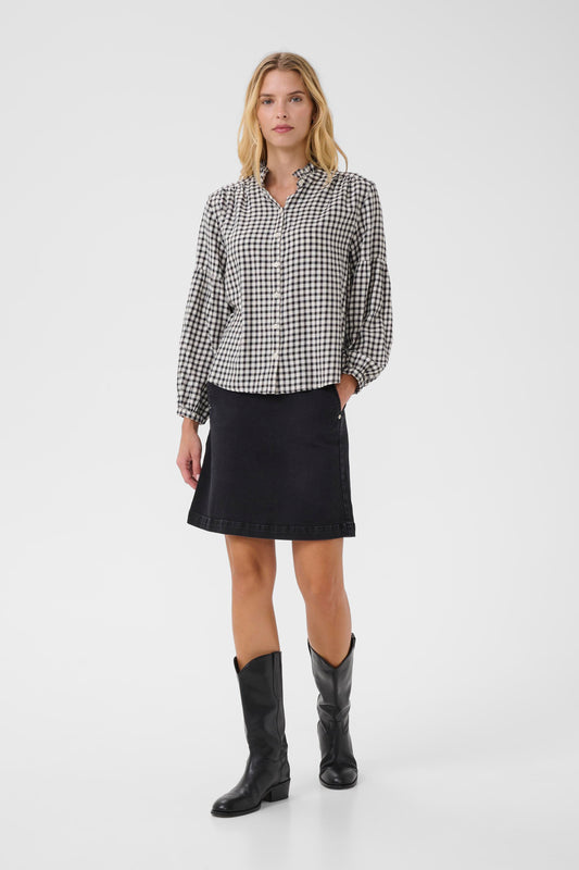 Woman wearing a checkered shirt, black skirt, and black boots on a white background