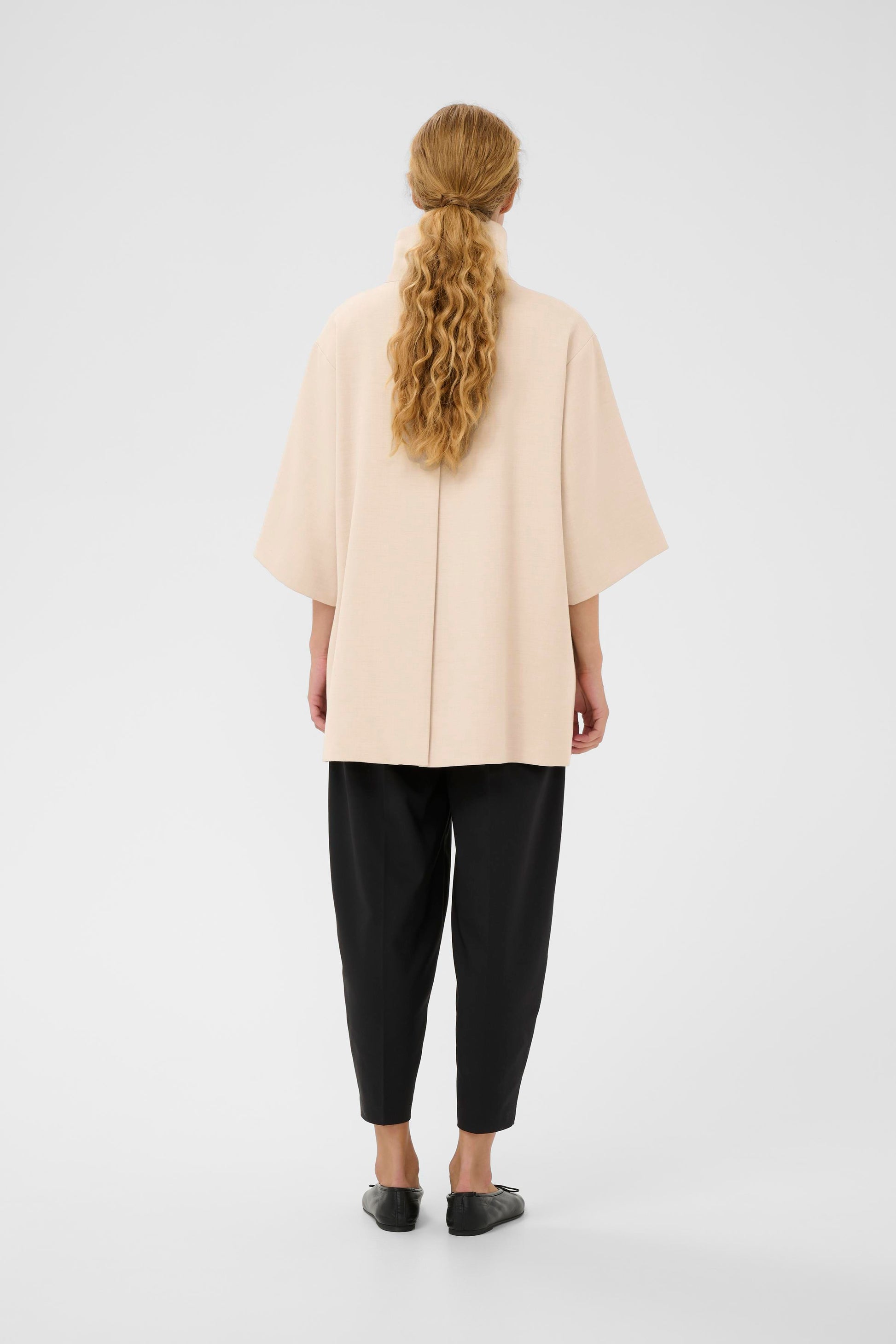 Woman wearing the InWear HollyN beige cape with black buttons on a white background