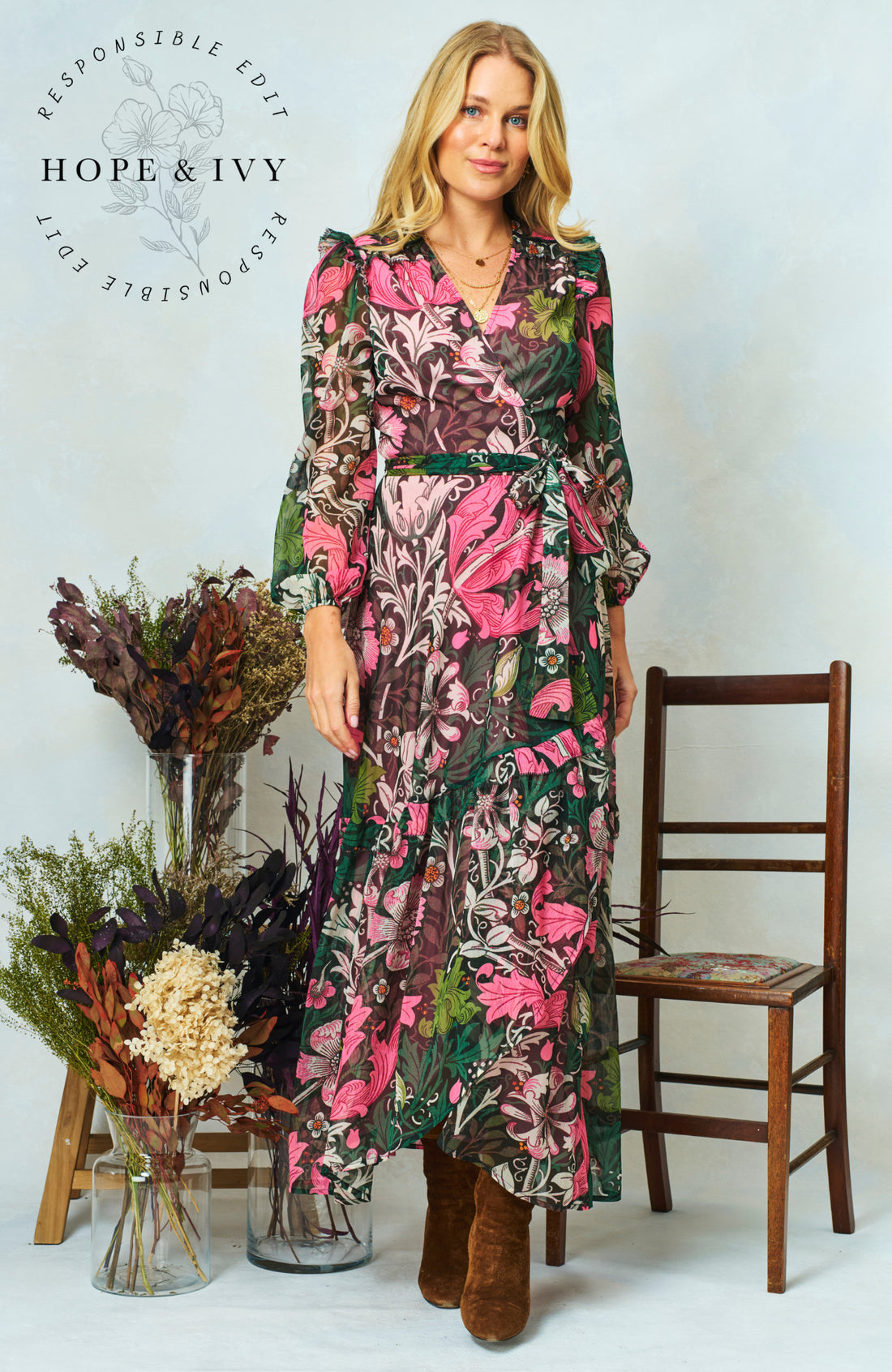 Woman wearing the maxi wrap floral Rosehip dress from Hope & Ivy.  Soft pinks, greens and black.
