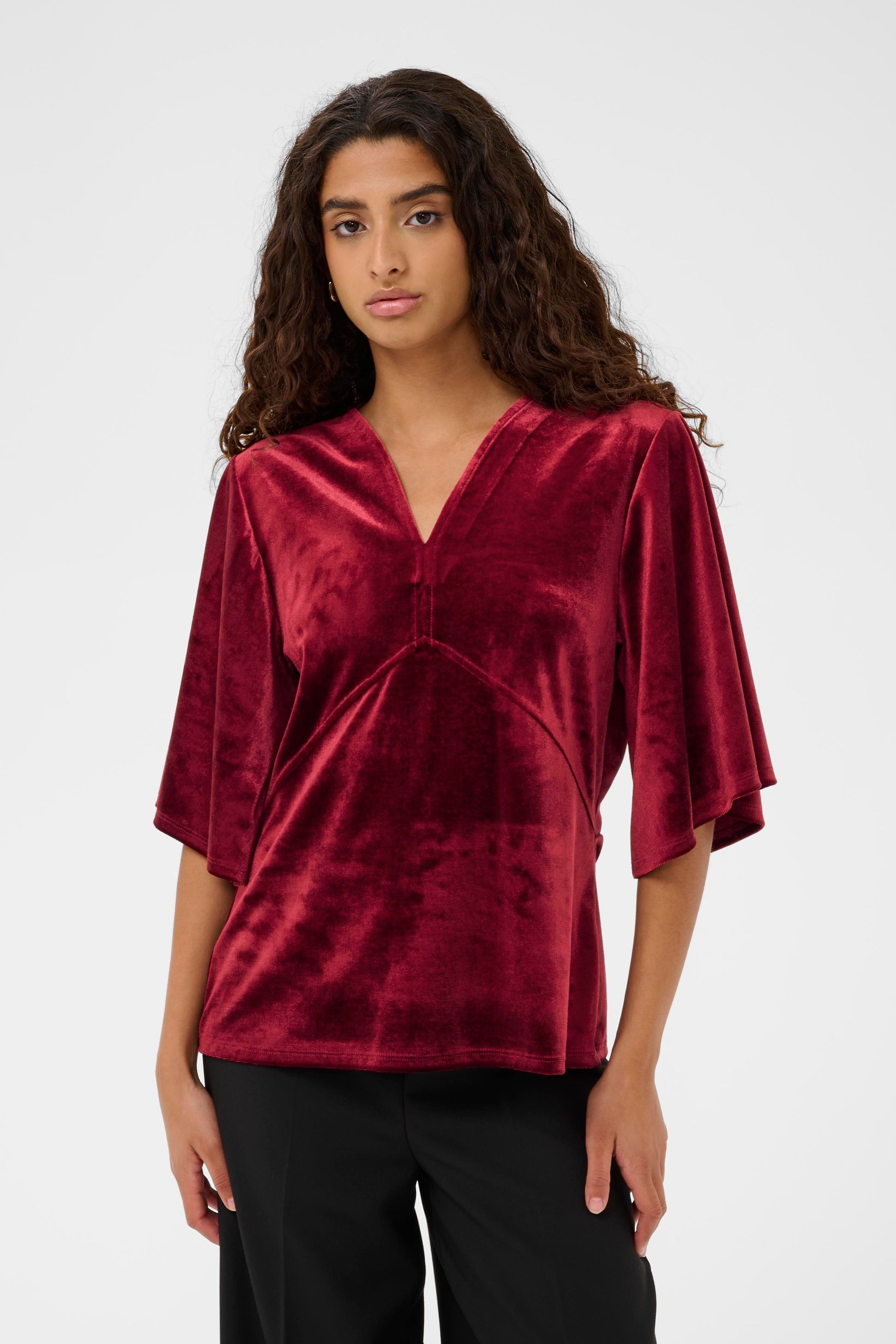 Woman wearing the Saint Tropez Velera burgundy velvet top against a white background