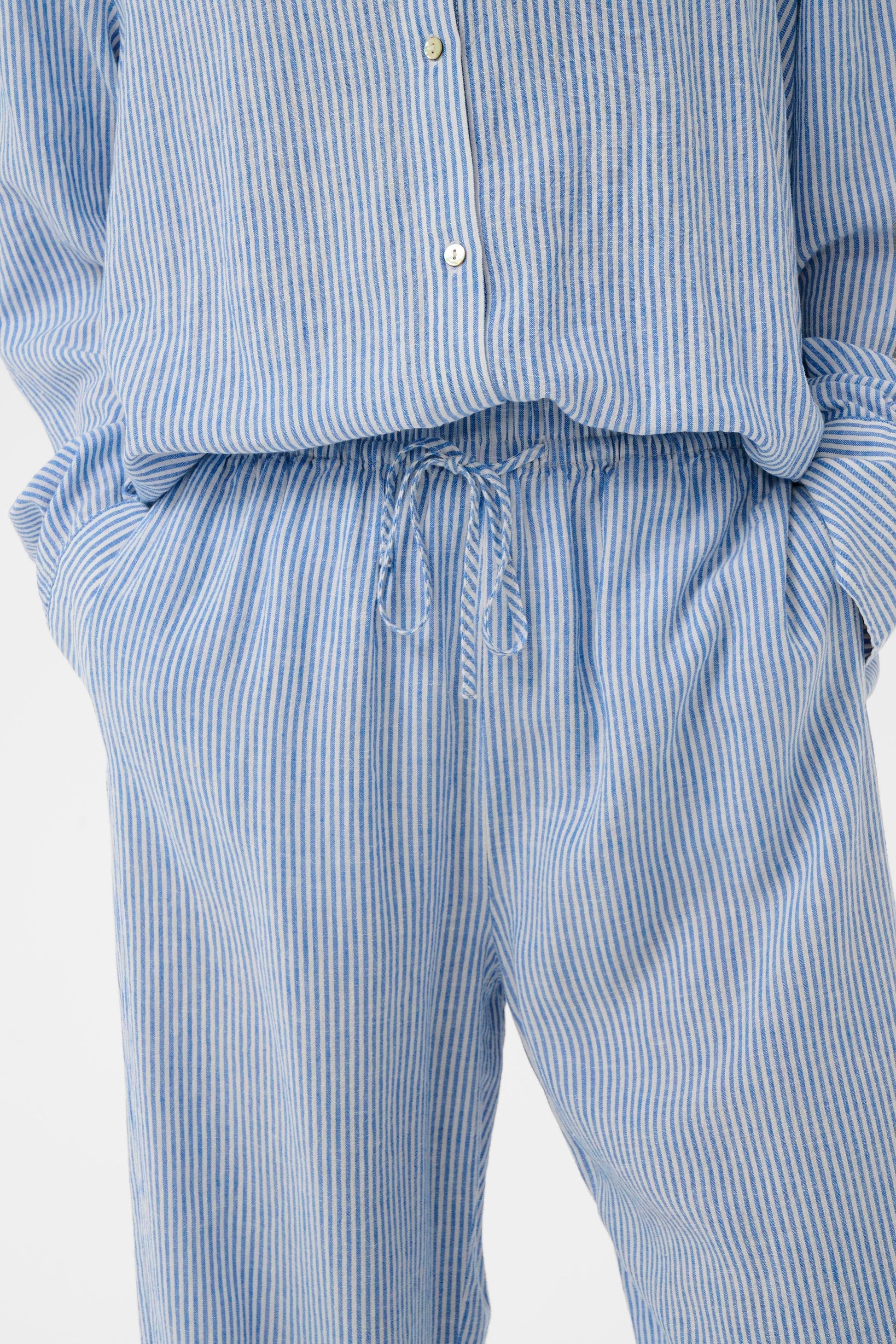 Woman wearing Soaked in Luxury Aria Blue with white fine striped linen trousers