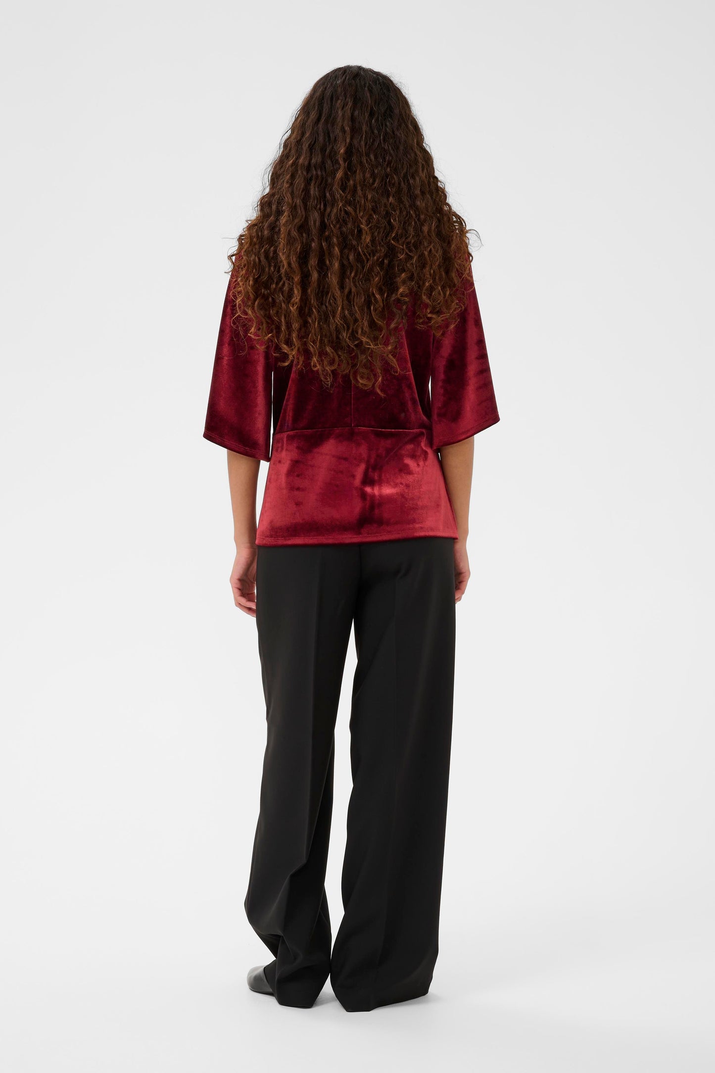 Woman wearing the Soaked in Luxury Velera burgundy velvet top against a white background