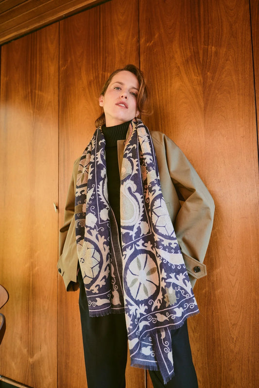 Woman wearing One Hundred Stars Wool Scarf wth a grey background and a susani print in lighter colour.
