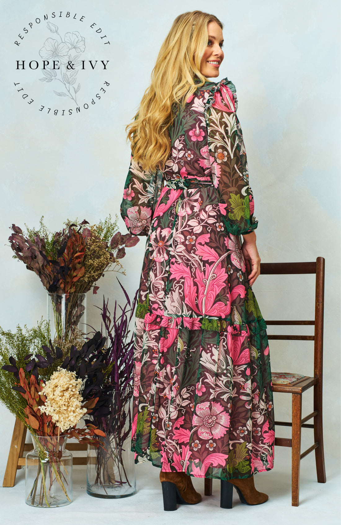 Woman wearing the maxi wrap floral Rosehip dress from Hope & Ivy.  Soft pinks, greens and black.