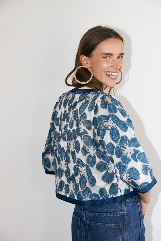 Trine feminine jacket featuring a woven floral design in blue, elegant tie-front fastening and wide sleeves.