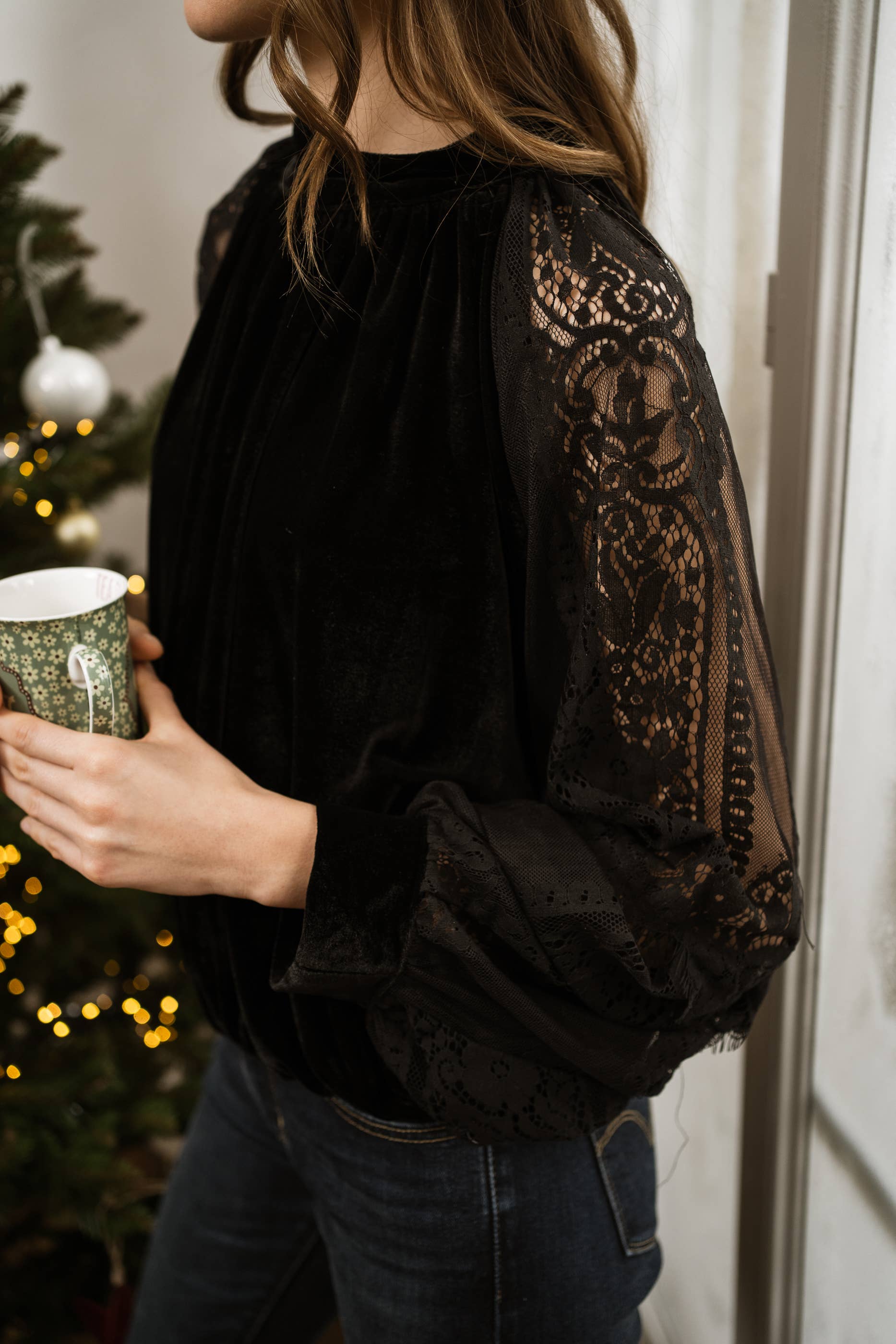 Woman wearing a black velvet top with lace sleeves from Chokolate Paris. 