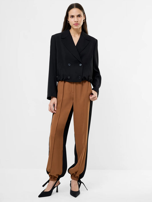 Women wearing a black cropped suit jacket with collar, 4 double breasted buttons and ruched bottom to jacket.  