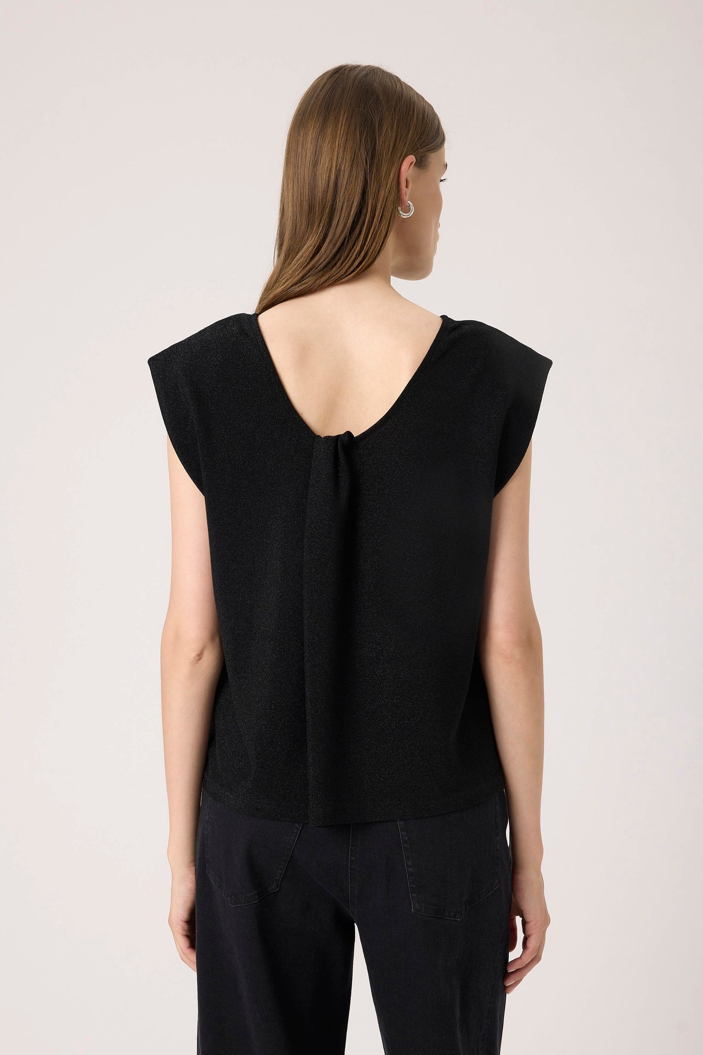 Woman wearing the Soaked in Luxury Skylara Tank top in black with metallic yarn  View from back of soft scoop back