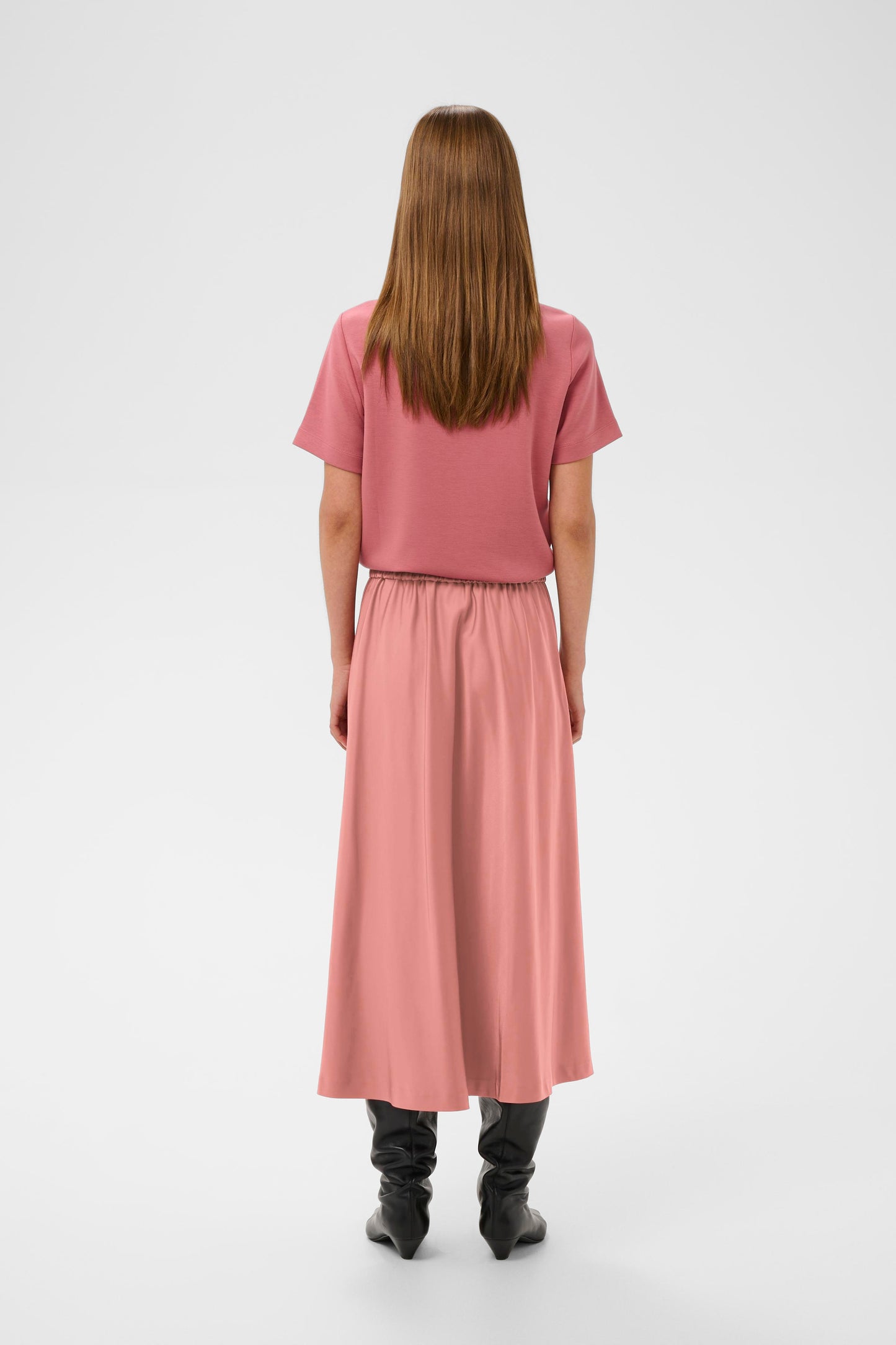 Woman wearing a pink sating skirt and pink Jumper