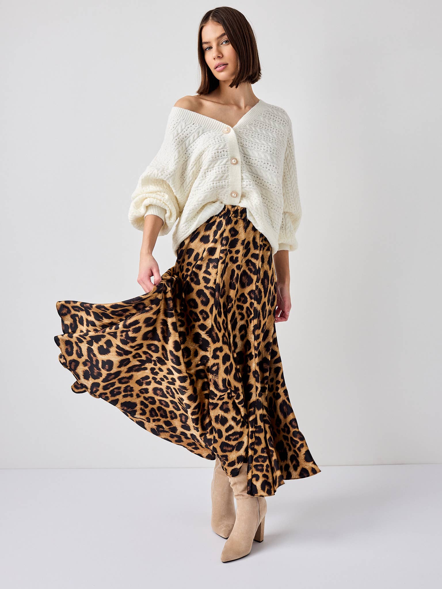 Woman wearing a white off-shoulder sweater and leopard print skirt on a white background